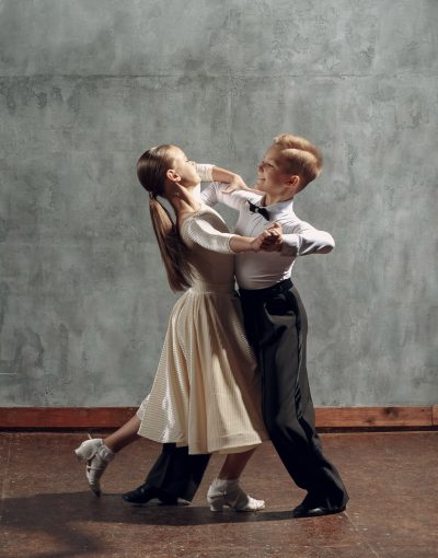 Young boy and girl dancing in ballroom dance Viennese Waltz.