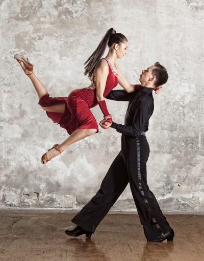 Dance beautiful couple dancing ballroom dancing on wall background. Toned image