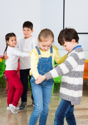 Pupils with teacher training dance movements Happy laughing pupils of primary school having fun during break with their teacher, training dance movements