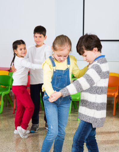 Happy laughing pupils of primary school having fun during break with their teacher, training dance movements